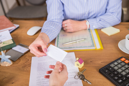Real estate agent gives a business card to customer, marking a successful investment in business of property, whether it be a house or an apartment. Real estate agent giving house key to customers.