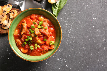 Bowl of tasty beef stew on black background
