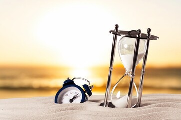 Antique sandglass in the sand on sea beach.