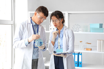 Young chemists with flask working in laboratory