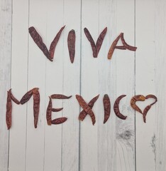 Viva Mexico sign written with dried chilies on white wooden surface