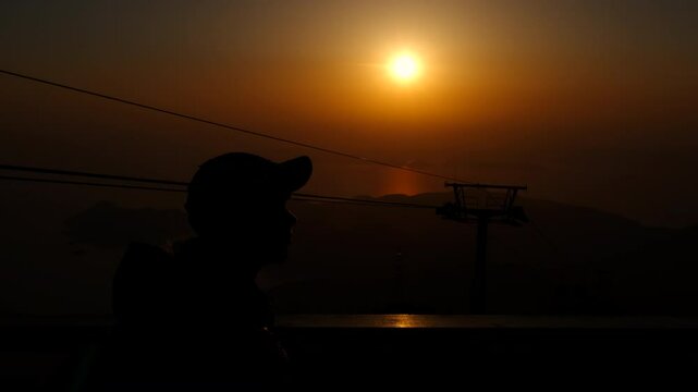 Teen silhouette enjoy nature from hill. Teeen girl silhouettes resting on the hill and enjoy the cable cars during holiday time.
