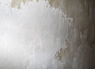 Textured wall with peeling paint revealing layers beneath in a softly lit interior space during...