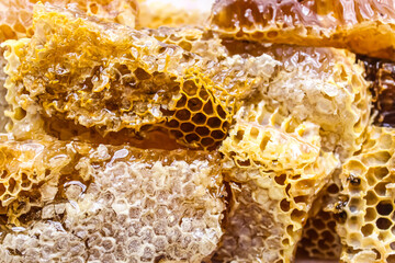 Close-up view of honeycomb produced by bees in a natural hive, showcasing the rich golden color and...
