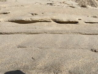 Uneven tracks in the sand with shadows