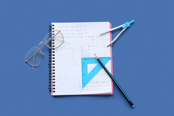 Notebook with eyeglasses and school stationery on blue background
