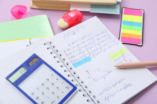 Notebook with calculator and school stationery on lilac background - Powered by Adobe