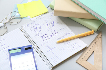 Notebook with calculator, eyeglasses and school stationery on grey background