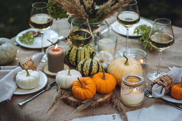 Fall table decoration with pumpkins, wine. Family thanksgiving dinner arrangement outdoors in the garden. Countryside style, simple handmade setting, autumn mood, inspiration