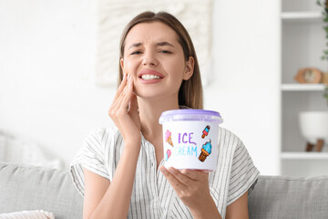 Young woman with cold ice cream suffering from tooth ache at home