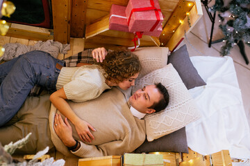 Top view of couple kissing and embracing while lying on the pickup trailer near Christmas presents