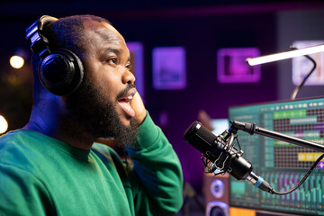 Confident artist singer performing a song on microphone in home studio, recording his audio files...