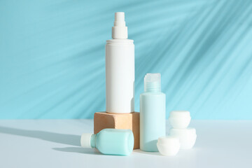 Travel cosmetic kit and palm leaf shadow on light table against color background