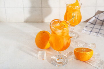 Glass of Aperol spritz cocktail and oranges on white table