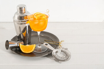 Glass of Aperol spritz cocktail and shaker on white wooden table