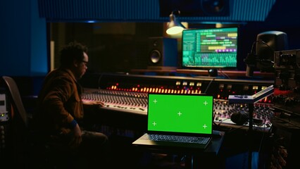Music producer recording tracks next to laptop showing mockup isolated display, working with mixing...