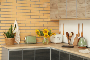 Vase with sunflowers, multicooker and toaster on counter in kitchen