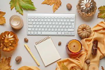 Composition with computer keyboard, blank notebook, burning candles and autumn decor on light background