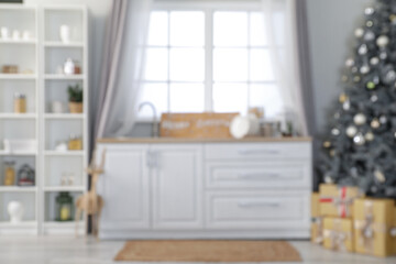 Blurred view of light kitchen with Christmas tree, counters and shelf unit