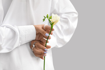 Woman with beautiful manicure holding freesia flower against grey background, closeup