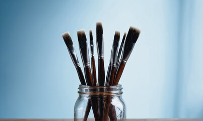A group of paintbrushes are gathered in a glass jar, ready for their next artistic endeavor
