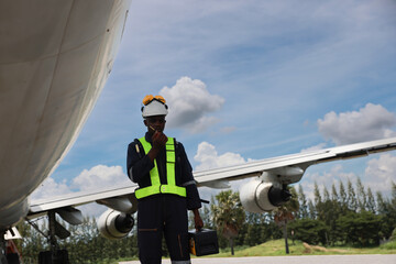 The black male aircraft mechanics use hand tools to work on inspection and do maintenance of an...