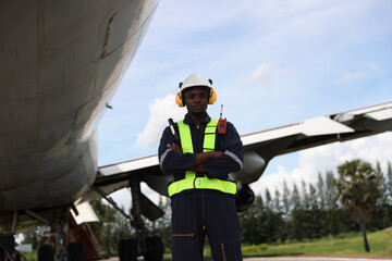 The black male aircraft mechanics use hand tools to work on inspection and do maintenance of an...
