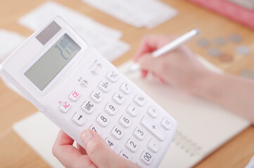 電卓でお金の計算をするミドル女性