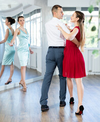 Man and girl take dance lessons from experienced teacher. Couple in stage costumes practices waltz...