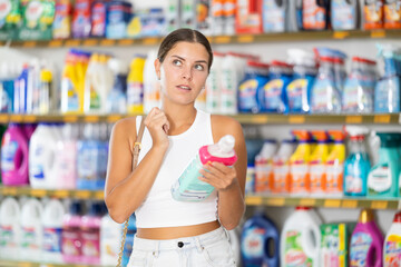 Woman carefully selects cleaning product in industrial section of a supermarket