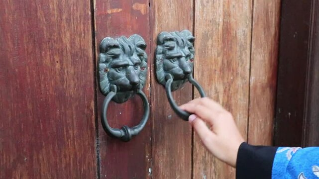 A woman's hand knocking on a classic traditional wooden door