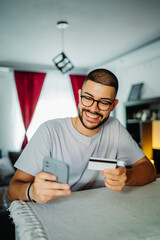 Young caucasian man shopping online on mobile phone using credit card