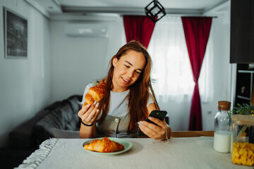 Young caucasian woman eating croissant for breakfast