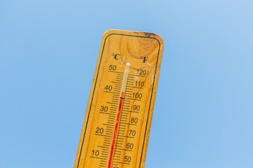 Thermometer displaying high summer temperature on a clear sky background
