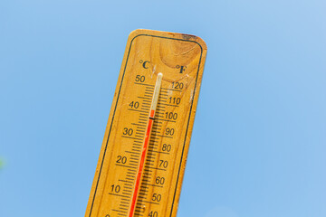 Thermometer displaying high summer temperature on a clear sky background