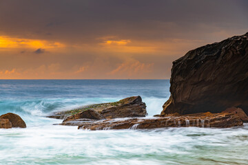 Sunrise at the seaside with rocks and beautiful diffused light by the rain clouds