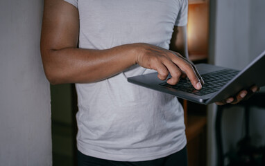 Close-up hands of asian male freelancer holding and typing on computer laptop keyboard.