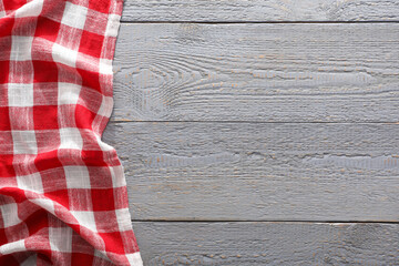Red checkered picnic tablecloth on grey wooden table, top view. Space for text