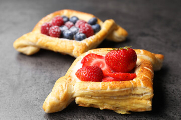 Tasty puff pastries with berries on grey table, closeup