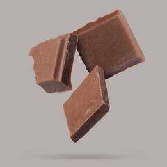 Pieces of sweet chocolate falling on grey background