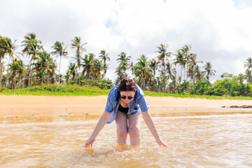 Fototapeta premium A woman over 60 enjoying and having fun in the beach water. The image represents older adults embracing life and breaking the stereotype of aging associated with limitations and inactivity