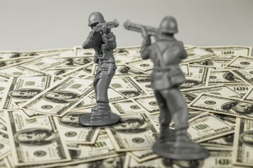 Toy soldier on US dollar bills banknotes, war costs concept