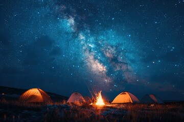 A group of tents are set up in a field with a campfire in the center