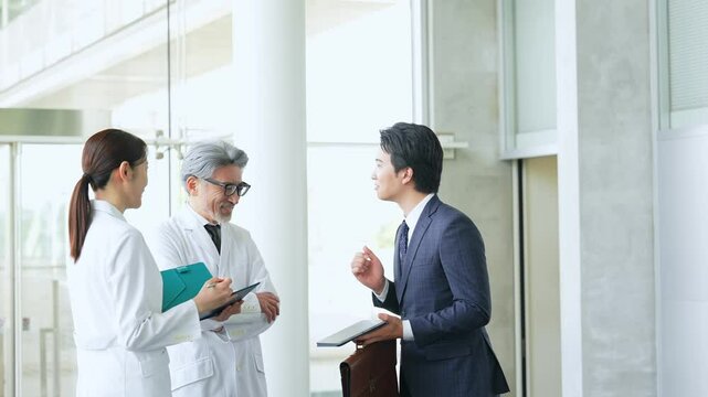 白衣の技術者に説明するビジネスマン