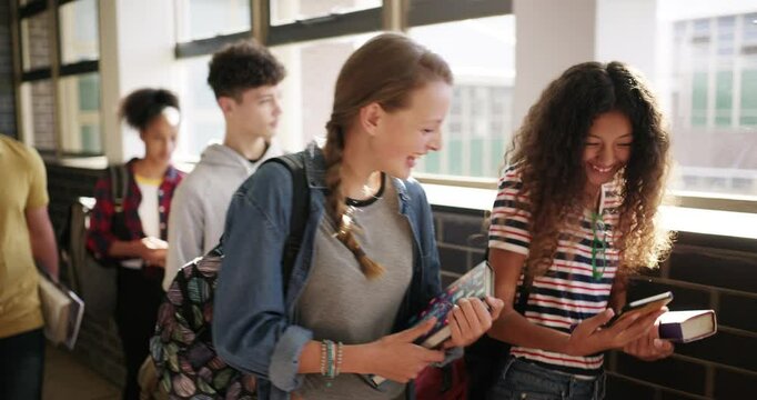 Education, phone and girl students walking in a hallway at school, talking or laughing at a joke together. Children, funny and a young friends in a corridor for scholarship, learning or social media