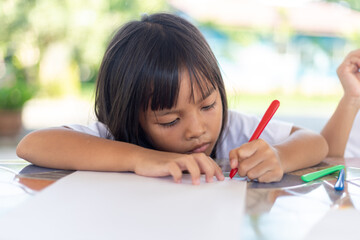 A young girl is drawing on a piece of paper with a marker.