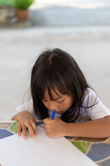 A young girl is drawing on a piece of paper with a marker.