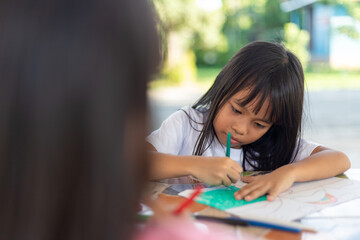 A young girl is drawing on a piece of paper with a marker.