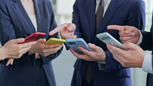 A group of business people using apps and watching videos on their smartphones