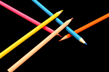 Several colored pencils lie on top of each other on a black background.